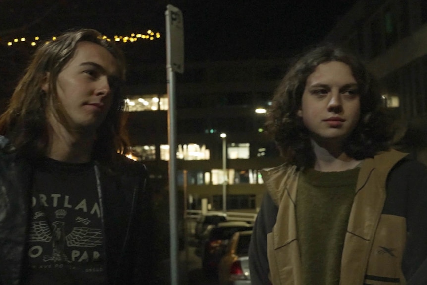 Two men standing in a street engaging in an interview.