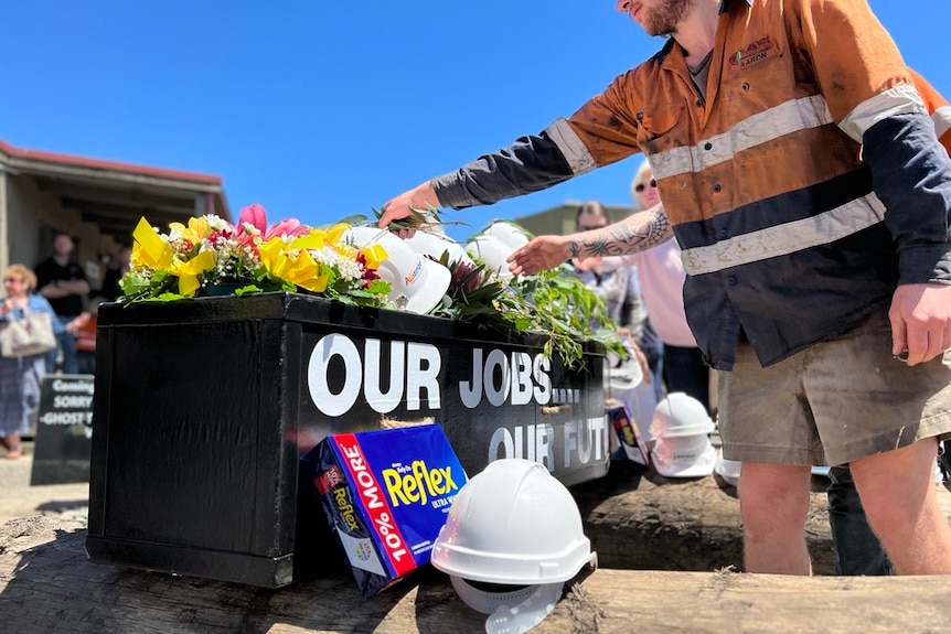 Workers protest ouside a timber mill, carrying banners and placards
