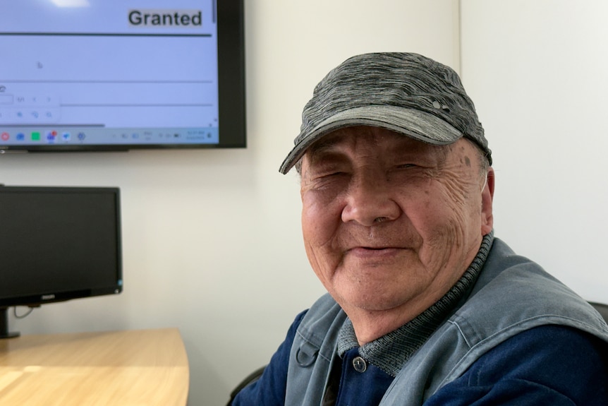 A headshot of Kwong Wan Lo wearing a hat and sitting in an office.