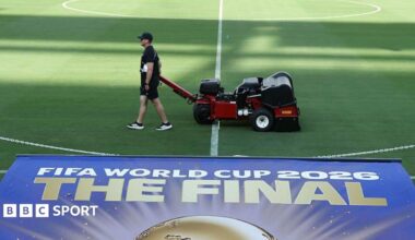 Staff attending to the field at the New York New Jersey Stadium with a sign for the 2026 World Cup final in the foreground