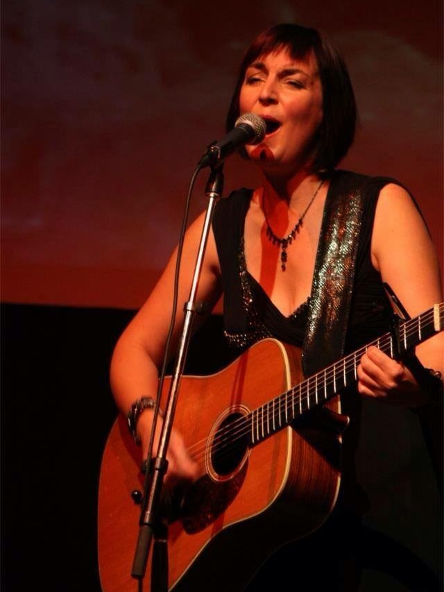 A female country musician singing on stage.