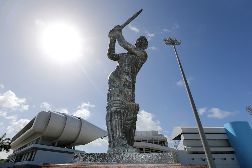 A statue of a cricket swinging his bat to hit a ball