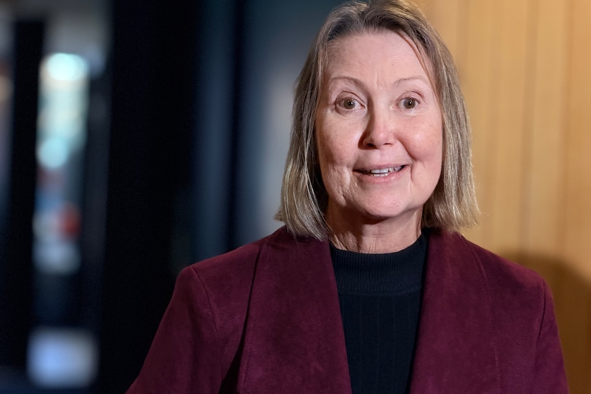 A woman wearing a red jacket is smiling.