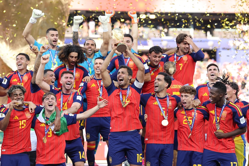 A man surrounded by teammates lifts the world cup in celebration