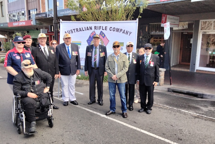 Men on street standing near a banner