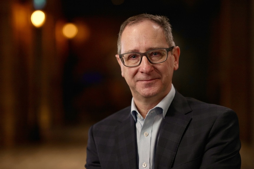 A man with glasses smiling