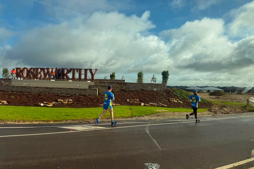 Two runners run on a road leaving Adelaide.