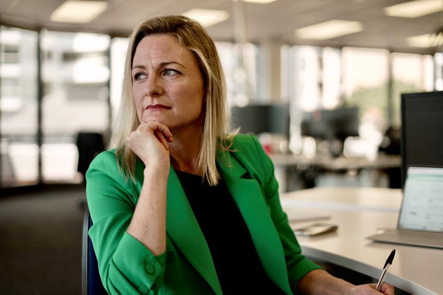 Sally Tindall seated in an office, wearing a green blazer