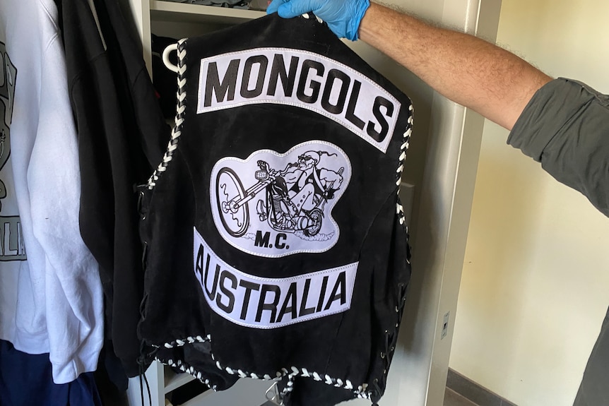 A police officer holds up a black vest reading Mongols Australia.