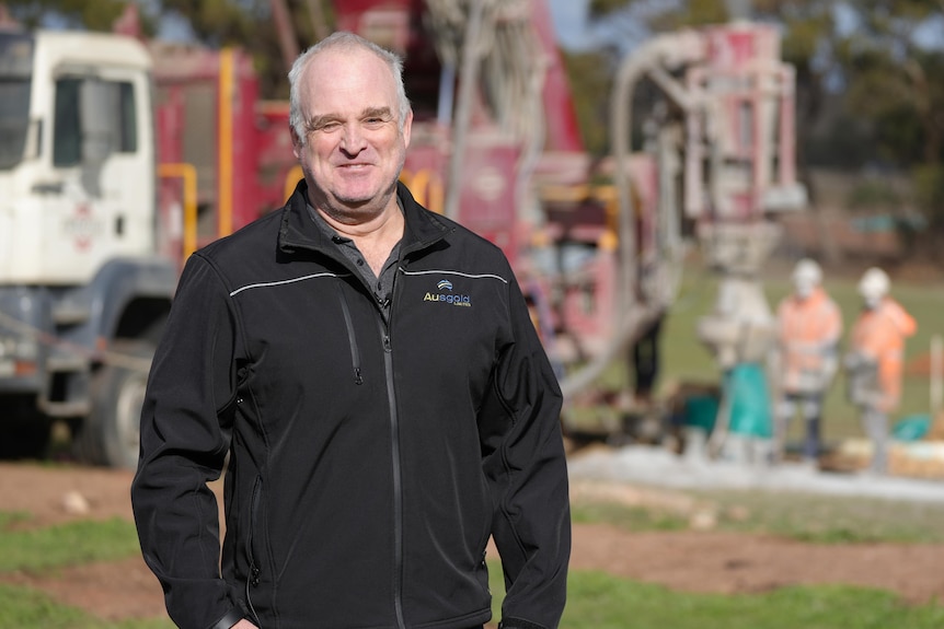 A man standing in front of a mining drill rig