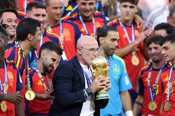 Luis de la Fuente kisses the World Cup trophy.