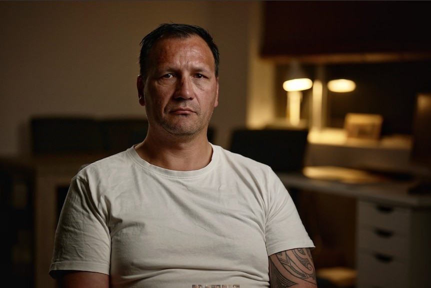 Man in a white tshirt stres at the camera