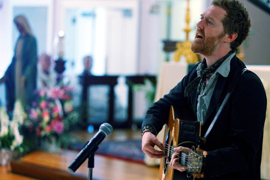 Glen Hansard singing and playing guitar.