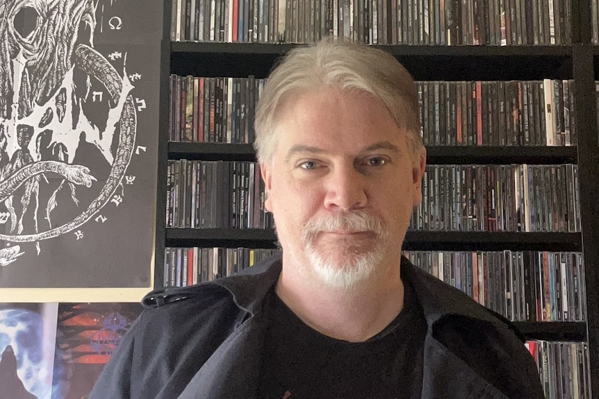 Man in black shirt looks at camera.