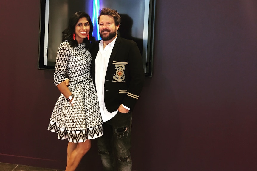 Huma wears a black and white patterned dress and Tom wears a collared shirt and blazer on the ARIAs red carpet.