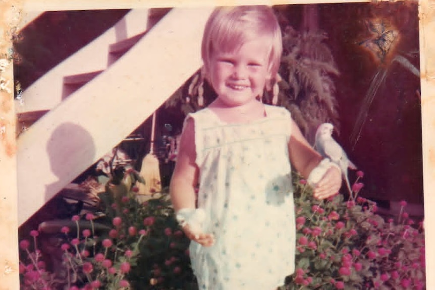 photo of blond child holding two budgies