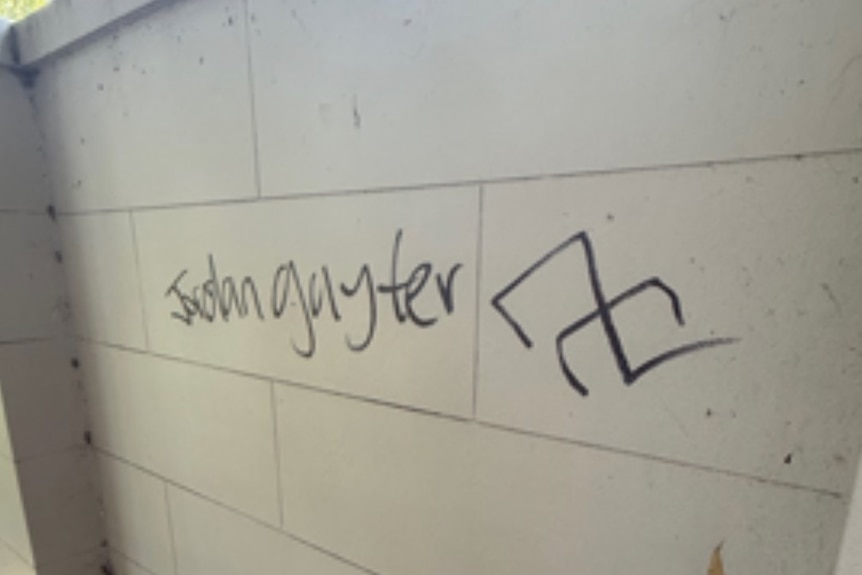 A swastika and German phrase on a wall.