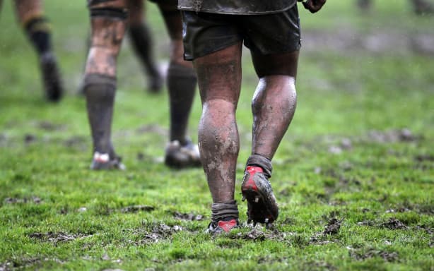 Players walk through the mud.