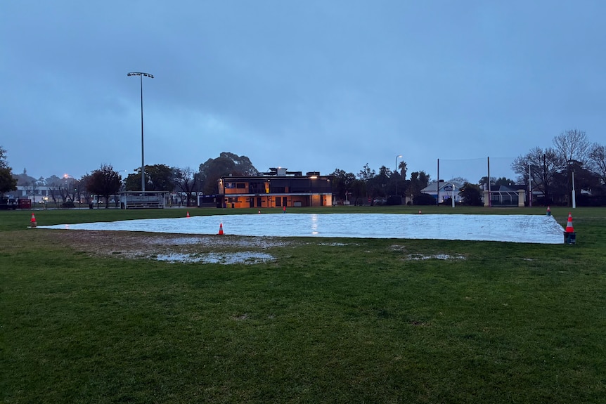 A large tarp covering muddy ground in a football field