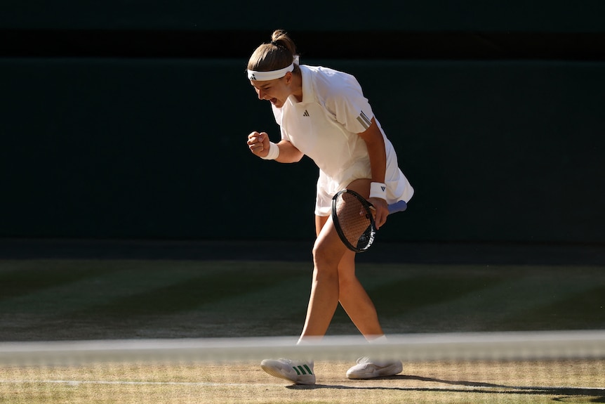 A young woman yells and pumps her fist in triumph on a tennis court.