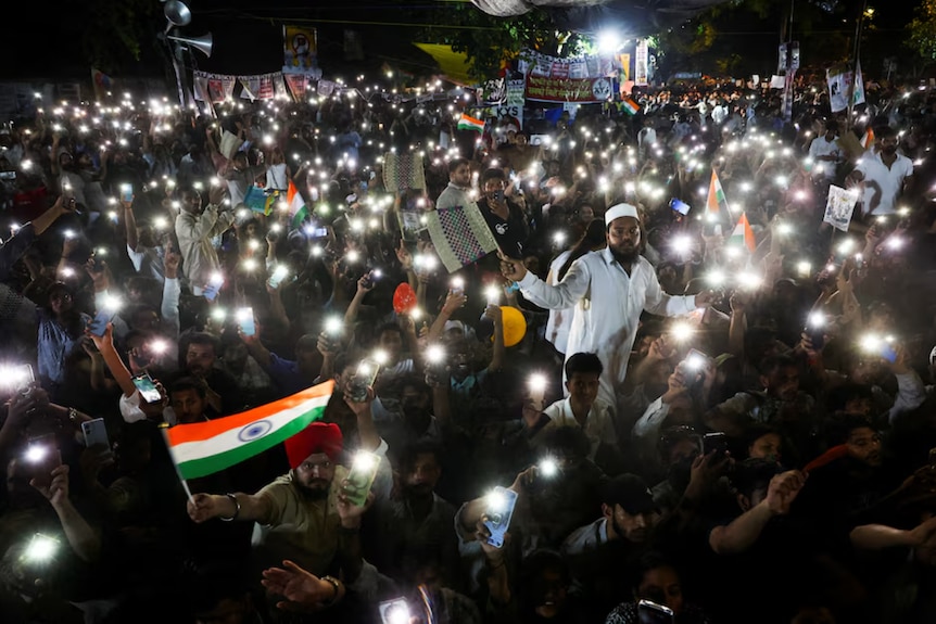 Large crowds of protesters wave their mobile phones with their flashlights at night
