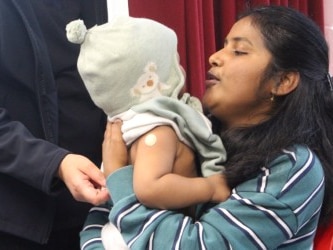 A woman holds her baby who's wearing a beanie