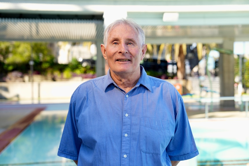 Max poses for a photo in a bright shirt, standing in front of an outdoor pool. 