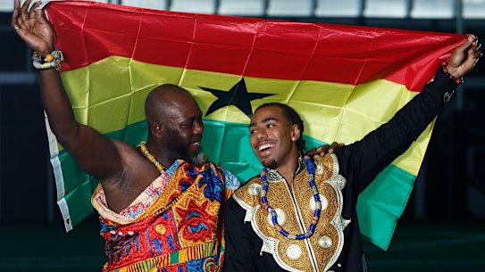 Father and son hold up the Ghanaian flag.