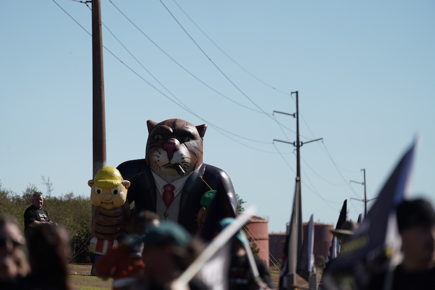 Workers march with a big inflatable cat in the background during the strike.