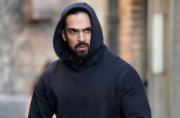 Ravi Gulati, wearing a black hoody with the hood up, in a scene from EastEnders
