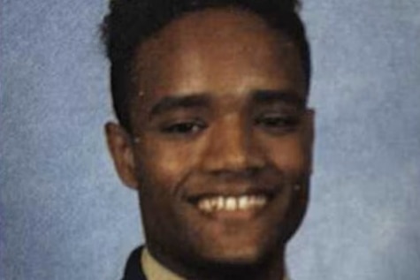 Photo of schoolboy smiling in front of grey background in portrait photo