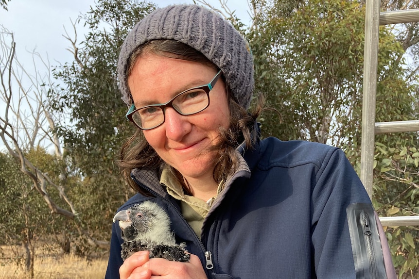 Zoe Kissane smiles and holds a juvenile bird