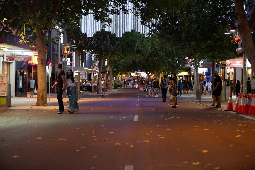 A street with pedestrians and diners lining the road.