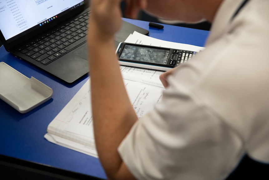 A maths student studies with a calculator on their desk.
