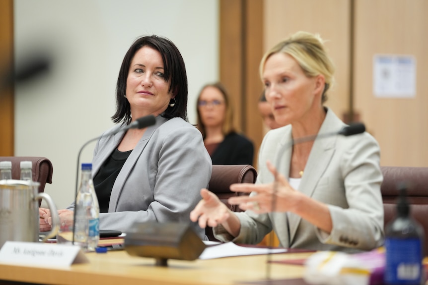 Two women sit at a desk.