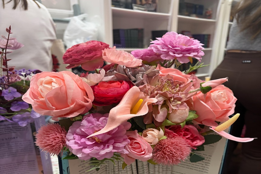A book with pages all folded up and flowers on top of it