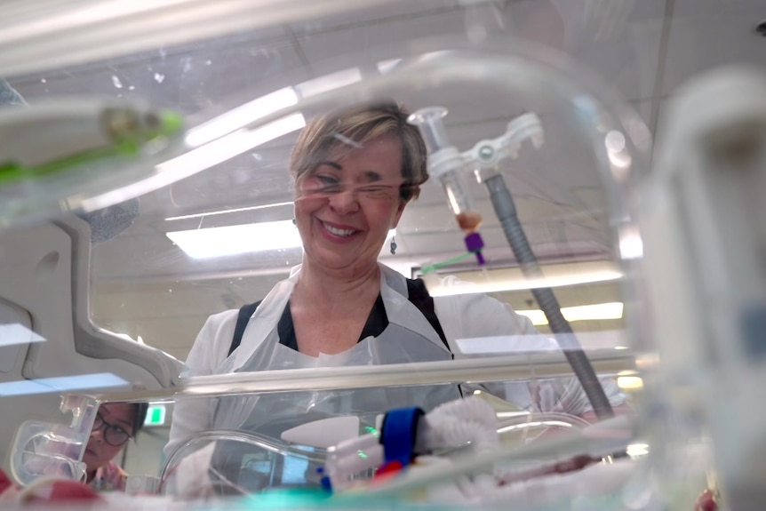 A smiling woman looks into a humidity crib