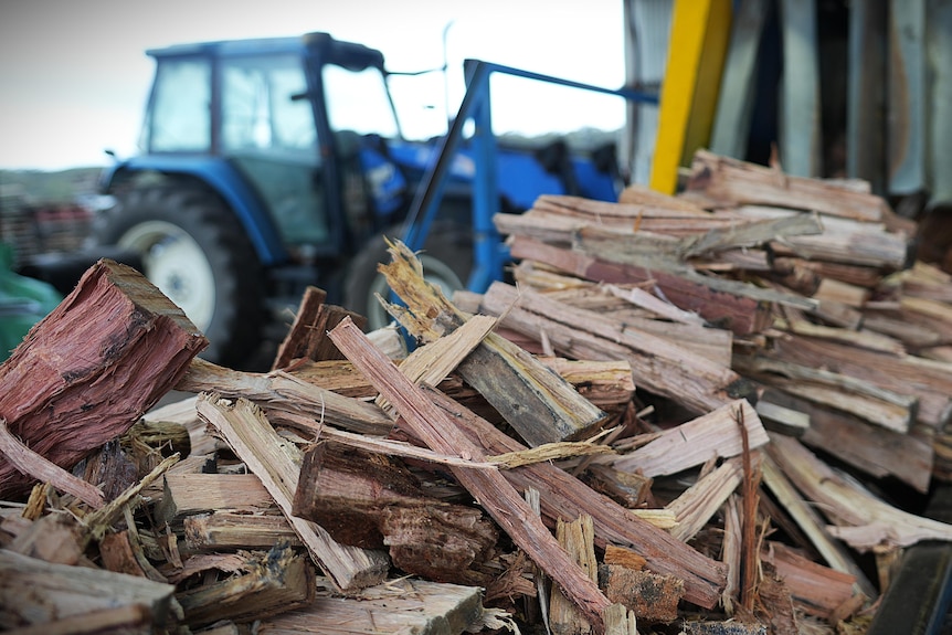 firewood pile, blue tractor in background