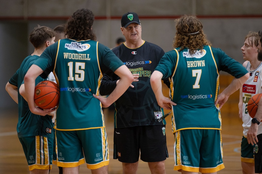 A basketball coach speaking to his players at practice.