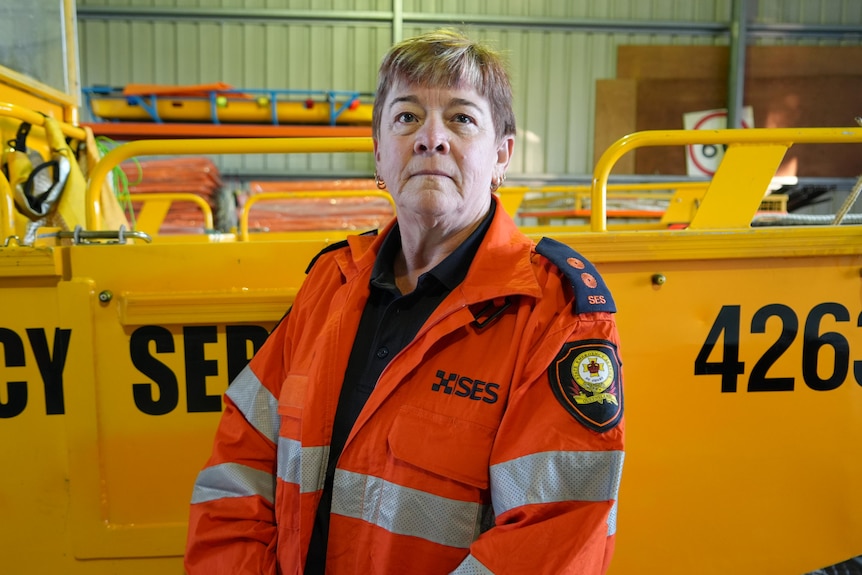 A woman in an SES jacket standing in front of a brightly coloured SES boat