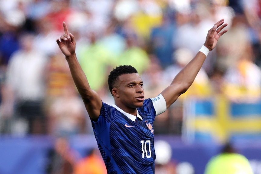 Kylian Mbappe holds his arms in the air in celebration