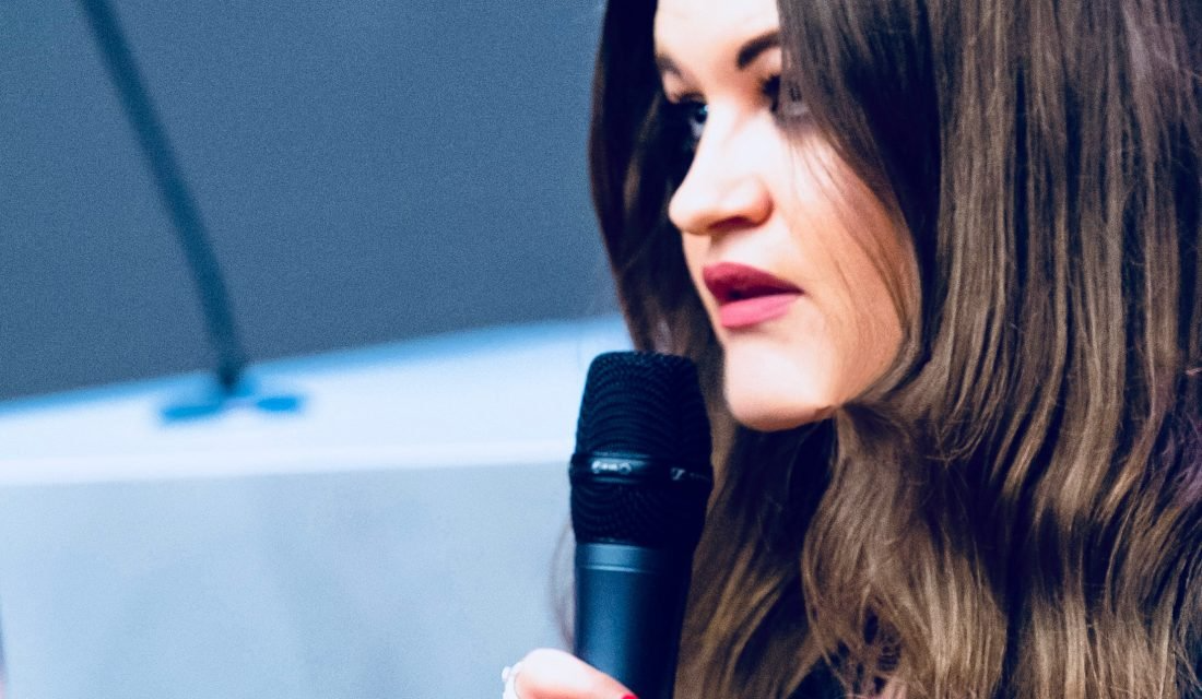woman with long hair holding microphone
