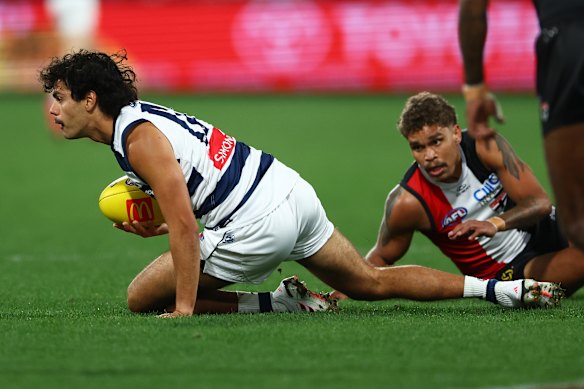 Lawson Humphries of the Cats breaks a tackle attempt from Liam Henry of the Saints.
