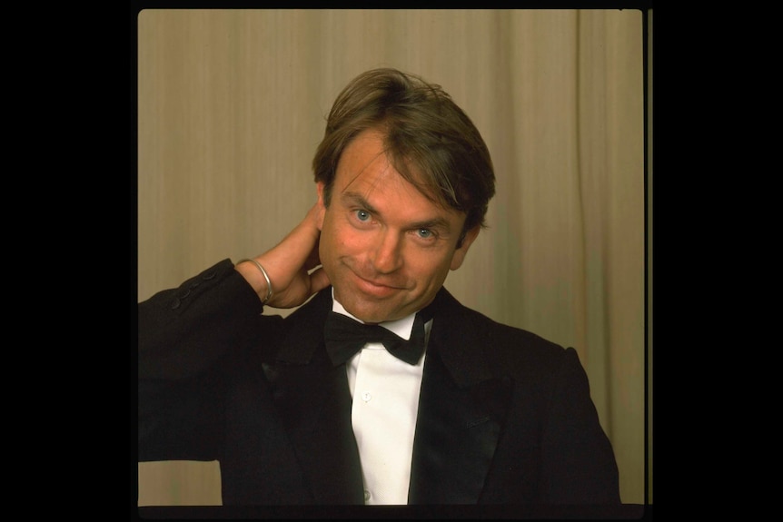 Young 1983 Sam Neill in a suit hand on the back of his neck