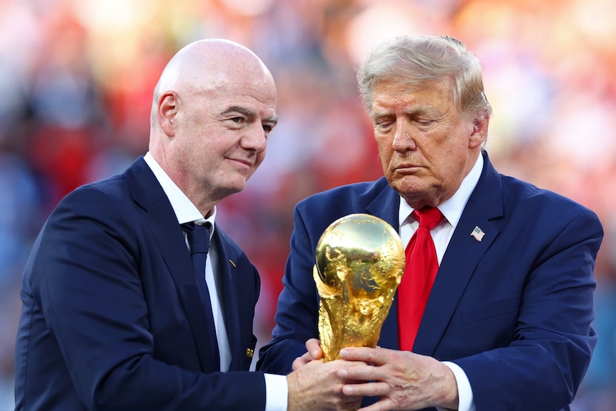 Gianni Infantino holds the golden World Cup trophy with Donald Trump.