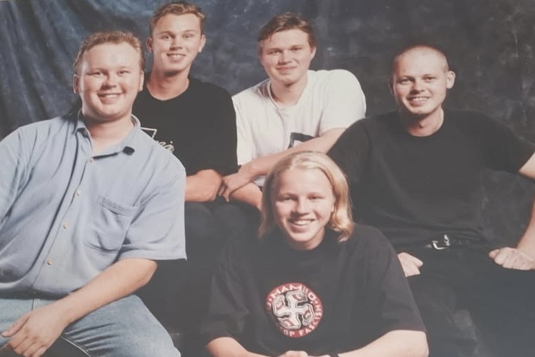five young seated men smiling at the camera. 