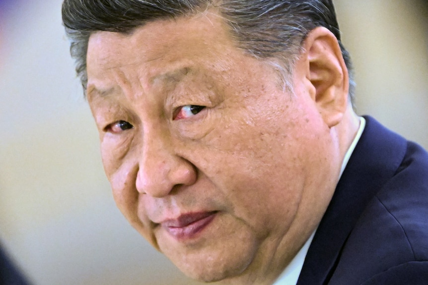 A close up photo shows the face of Xi Jinping.