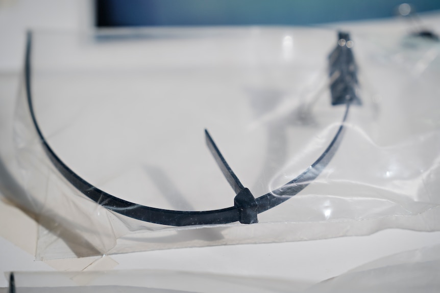 A close up shot of black cut cable tie inside a clear evidence bag resting on a white table.