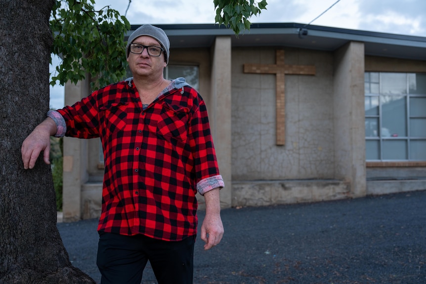 A man stands outside a building with a crucifix on the front of it.