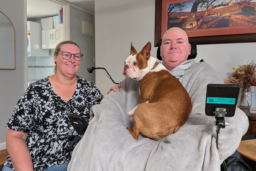 Jason Smith in wheelchair with wife Anthea and their dog at home